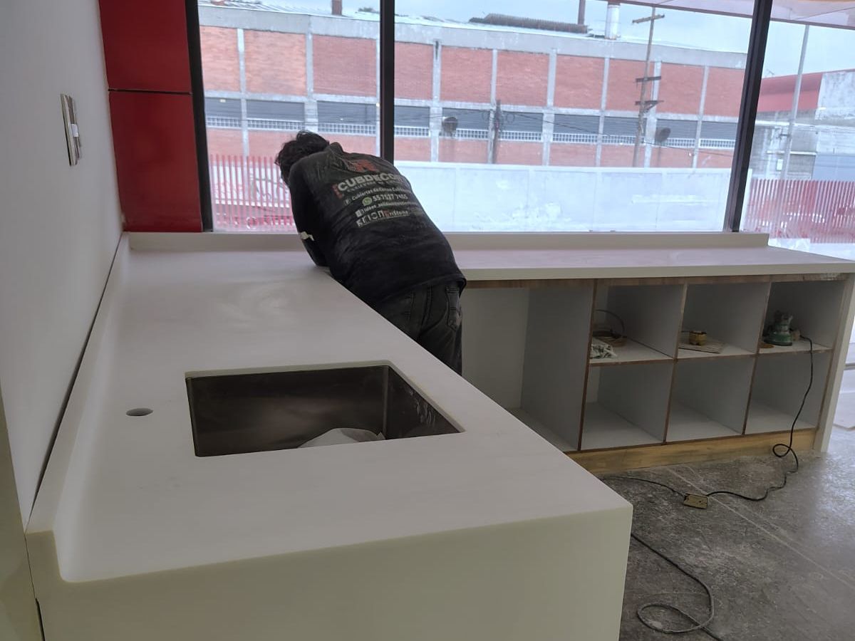 Instalador trabajando sobre una cubierta blanca con tarja de acero junto a un ventanal