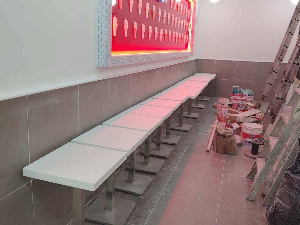 Barra corrida de cubierta blanca con patas de acero a lo largo de una pared