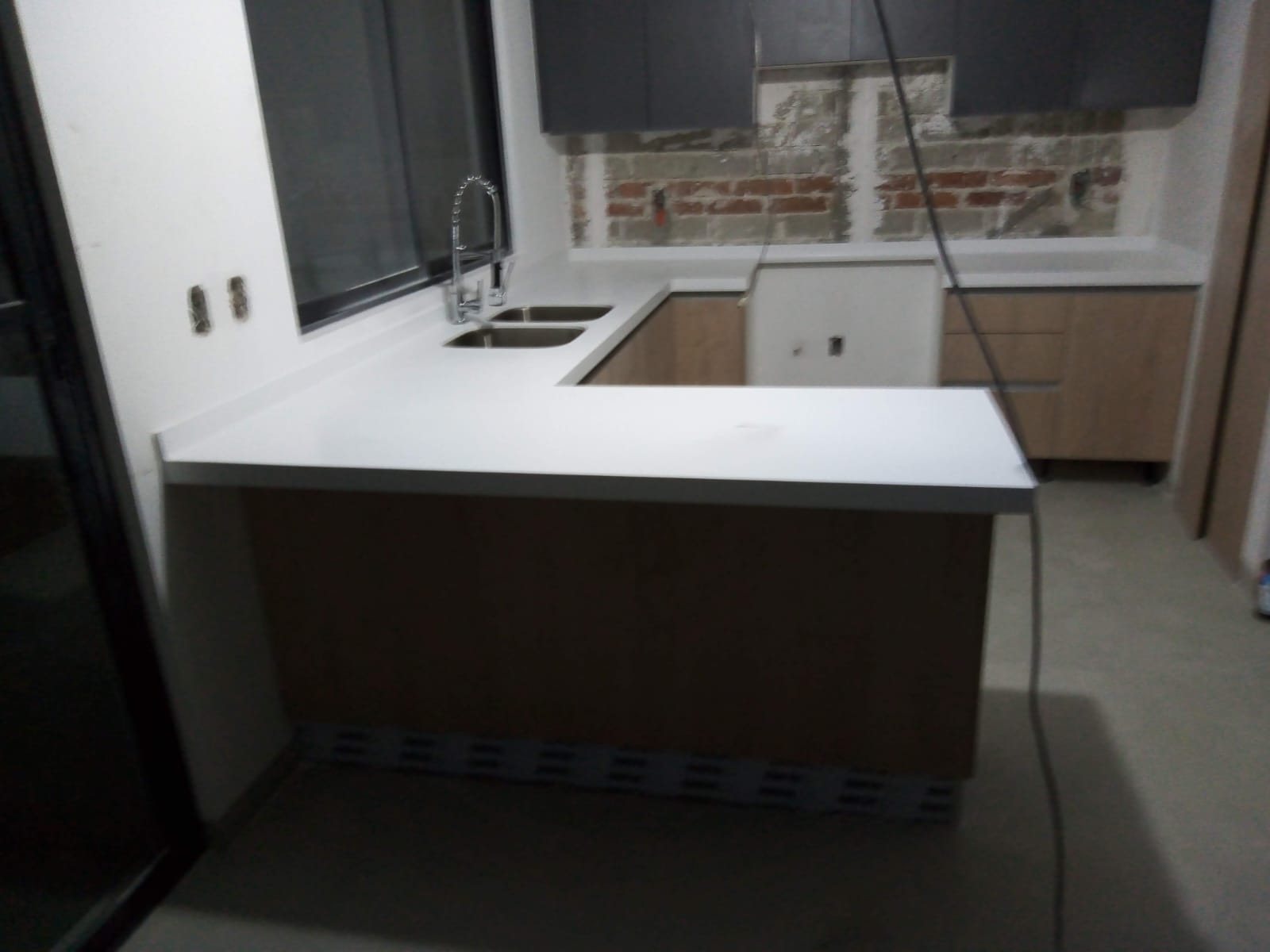 Cocina en U con cubierta de Corian blanco, barra y doble tarja de acero
