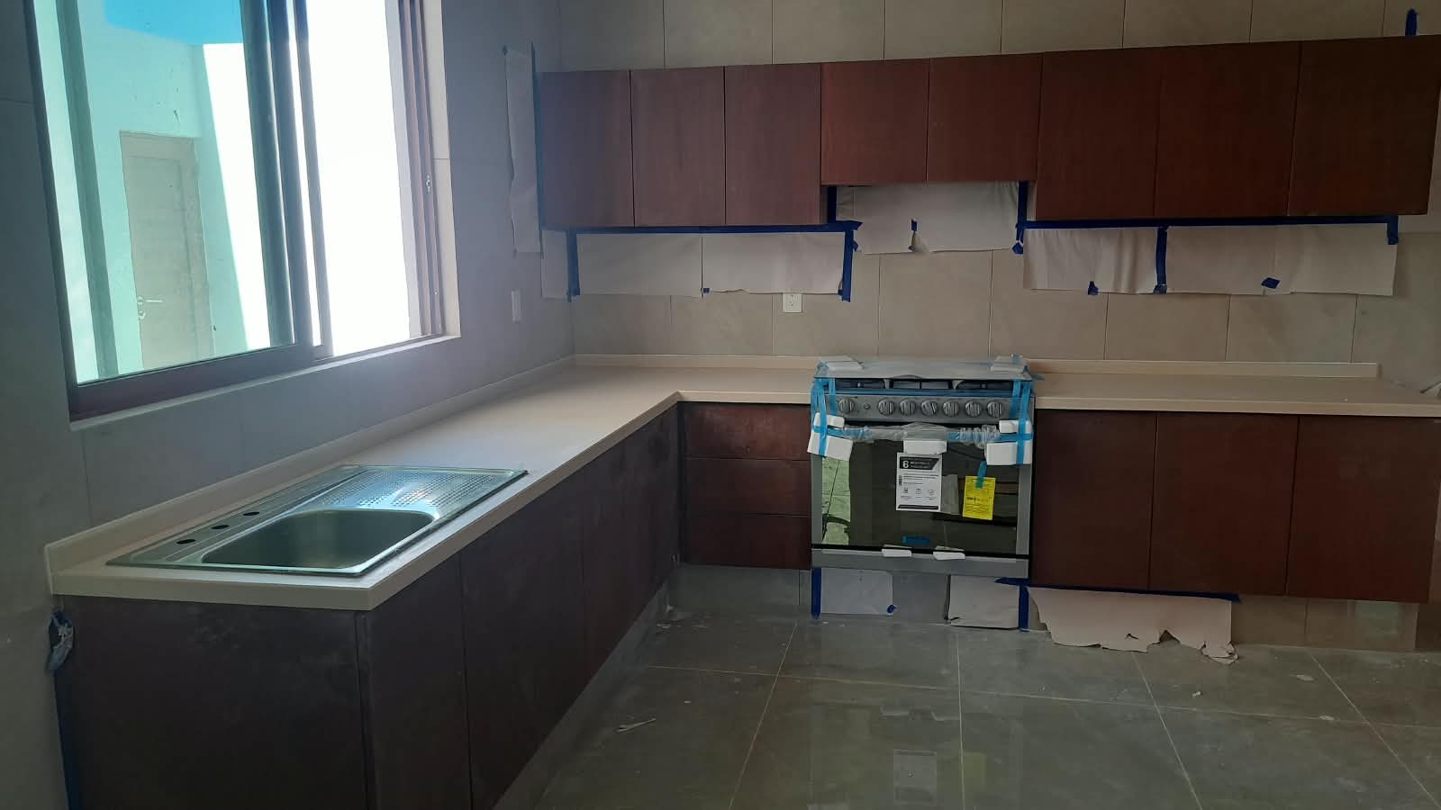 Cocina en L con cubierta de Corian color arena y tarja de acero