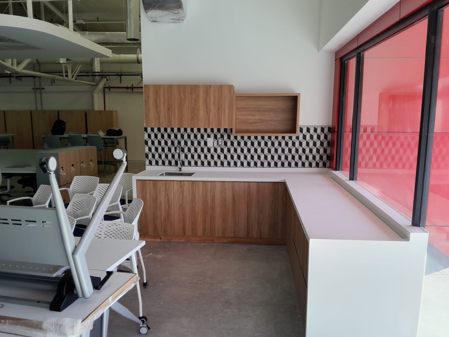 Cocineta en L con cubierta blanca y muebles de madera junto a un ventanal