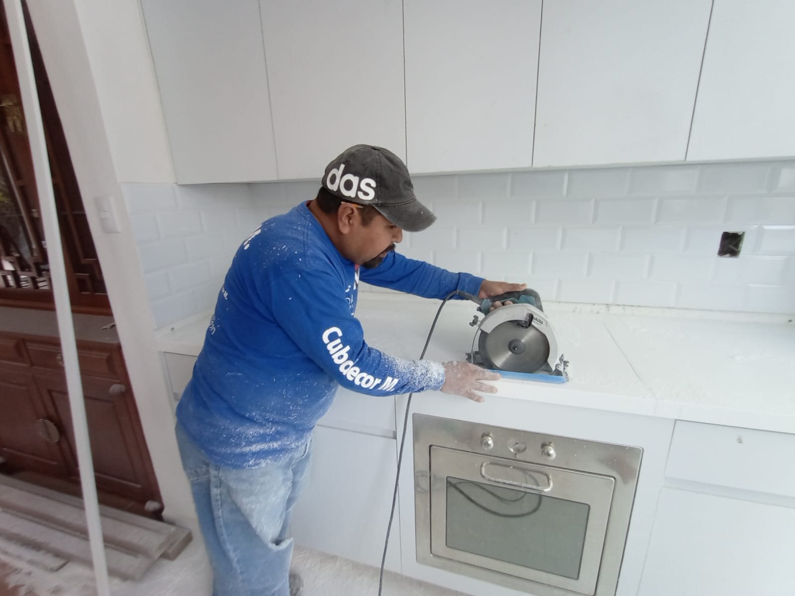 Instalador de Cubdecor cortando una cubierta de Corian en una cocina blanca